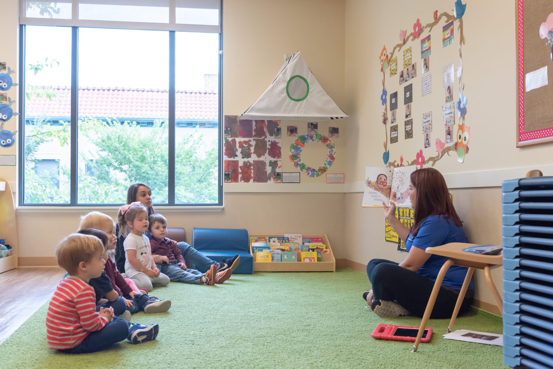 preschool teacher reading to semi circle of preschool students