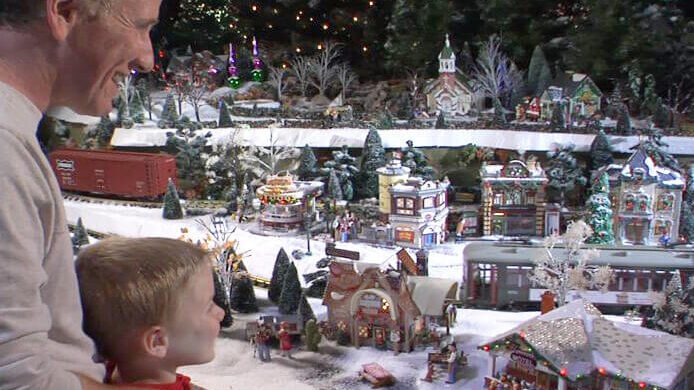 father and son looking at holiday train village display