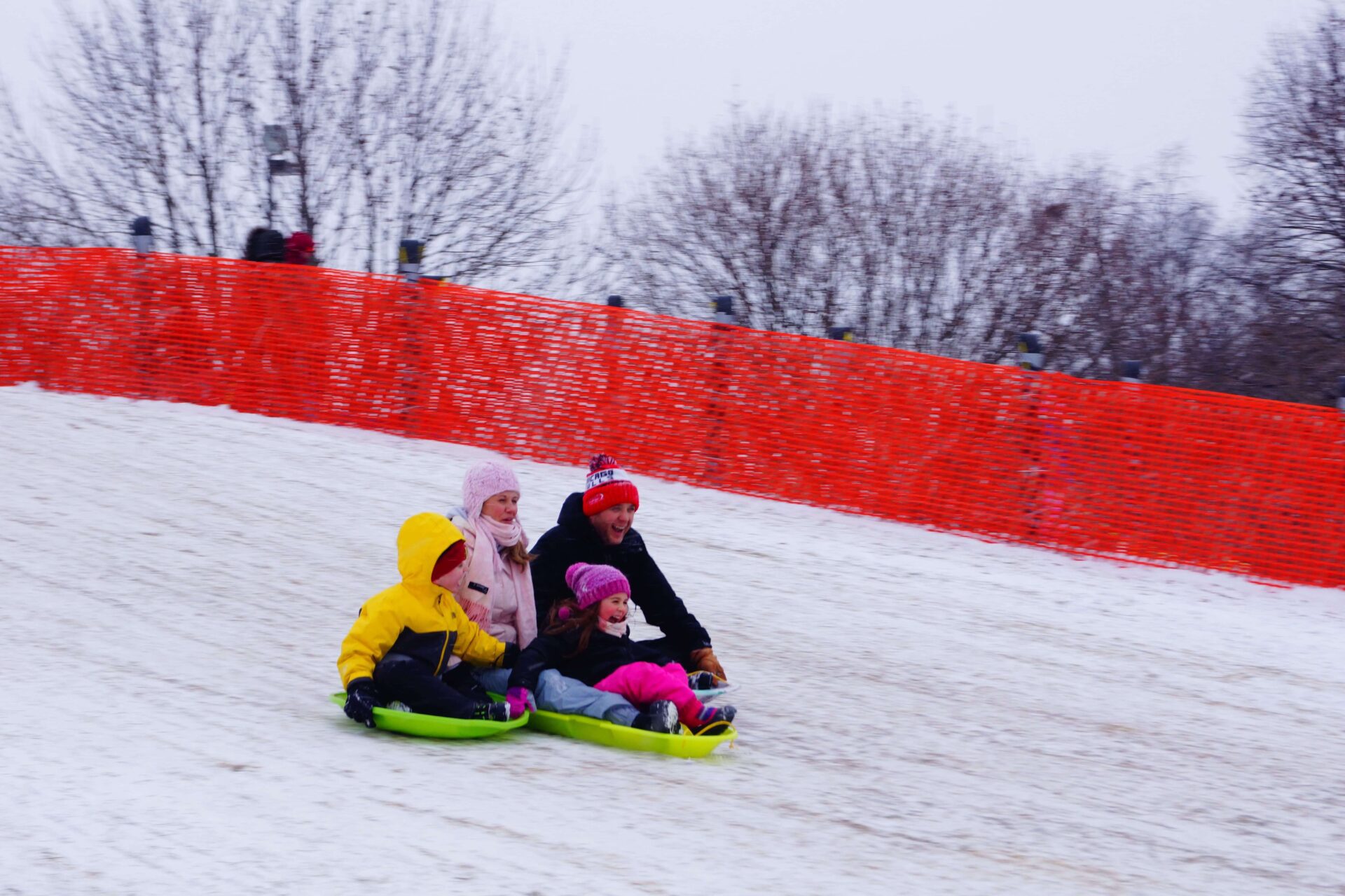 family sledding down hill at Riverwalk Sled Hill in Naperville