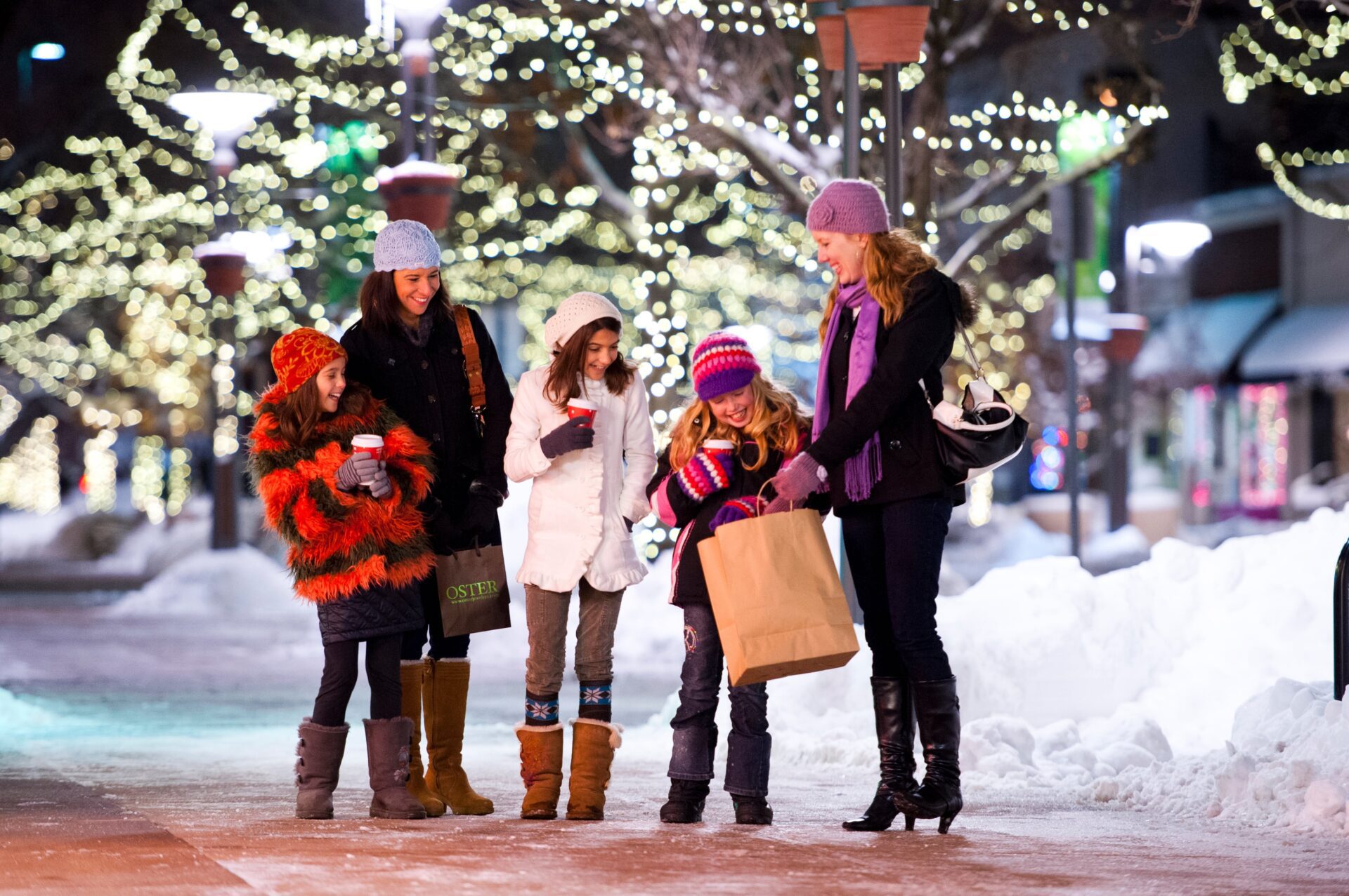 3 girls and 2 women holding shopping bags and coffee cups