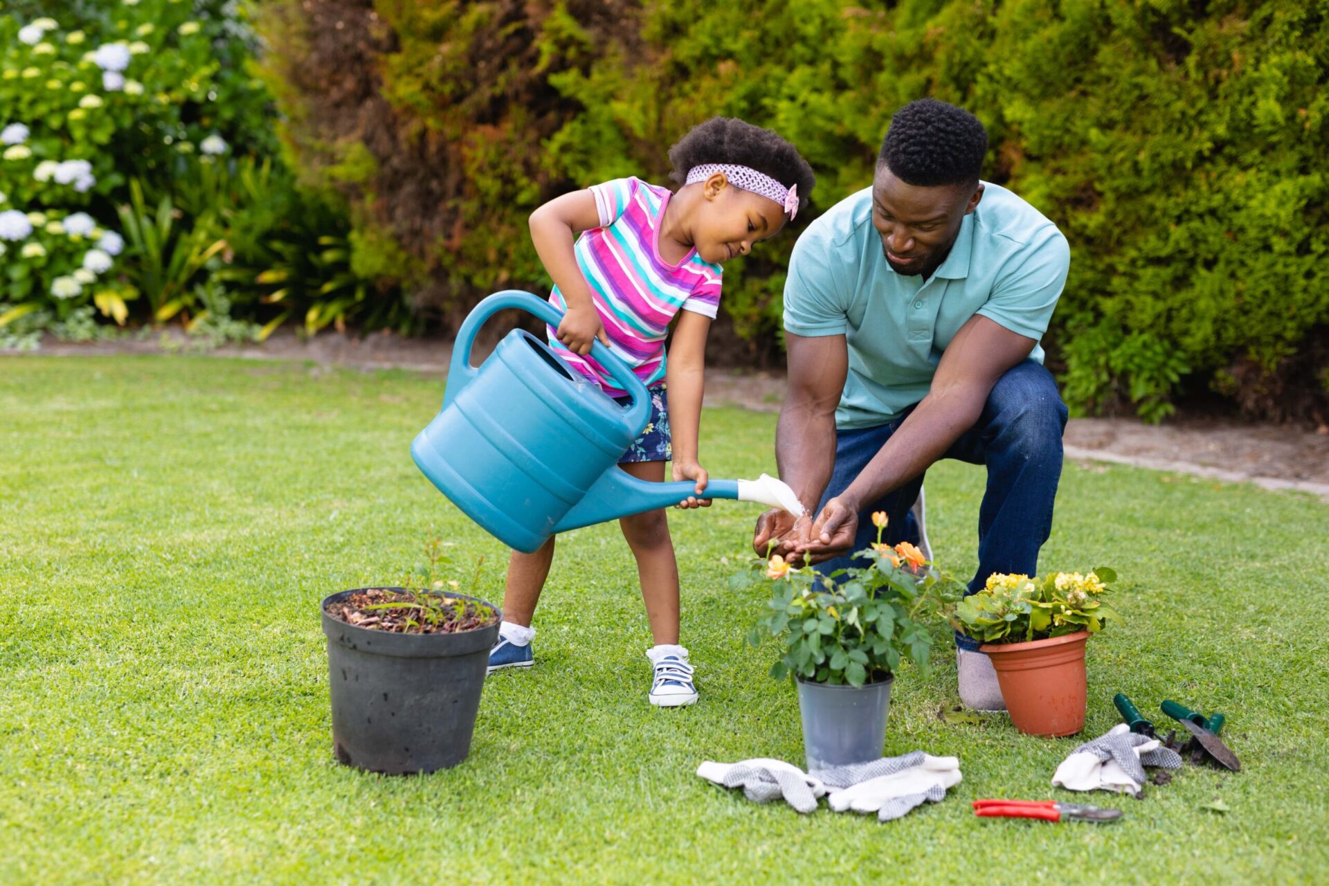 dad helping daughter water spring flowers