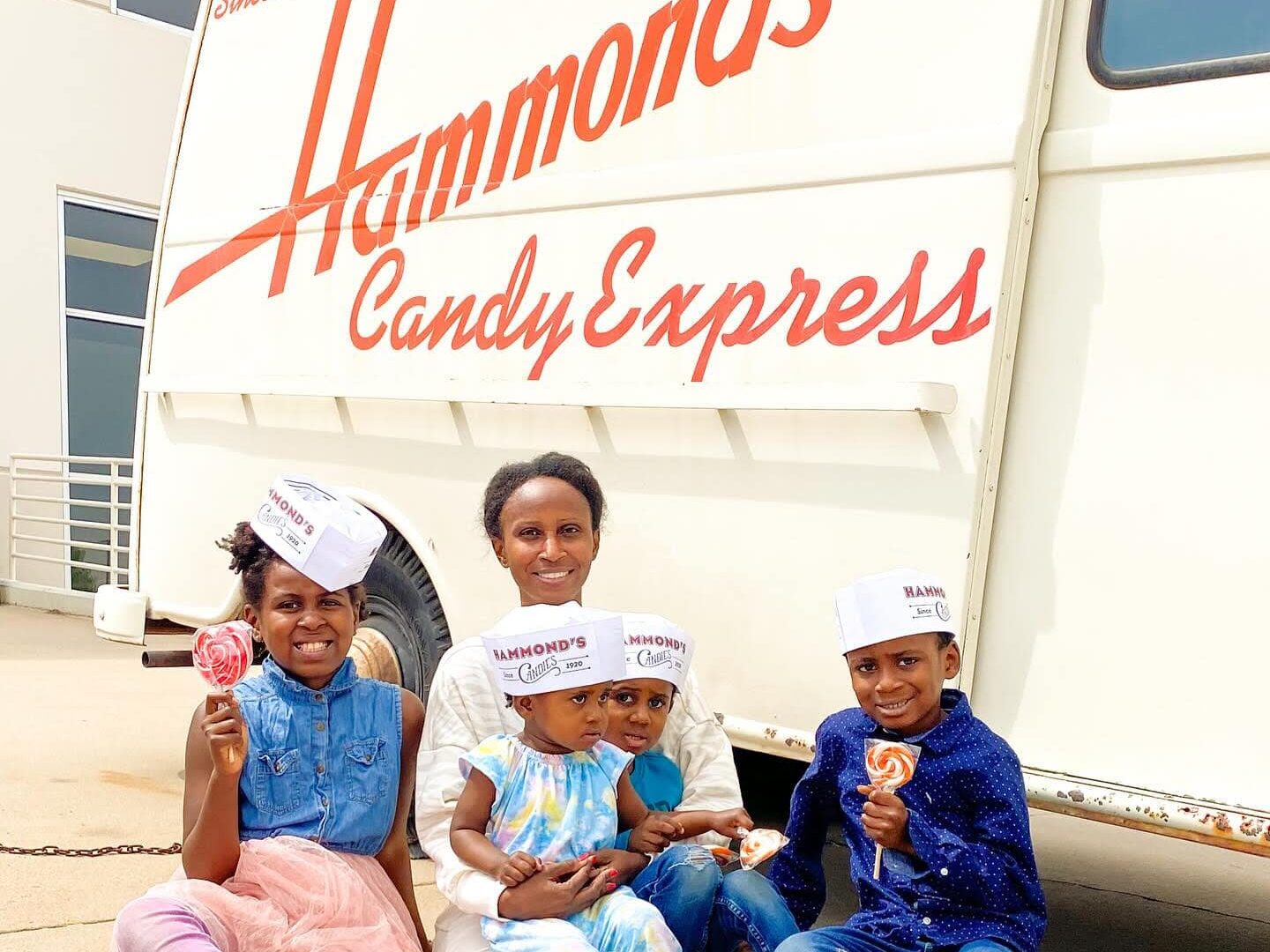 family holding lollipops in front of Hammond's Candies