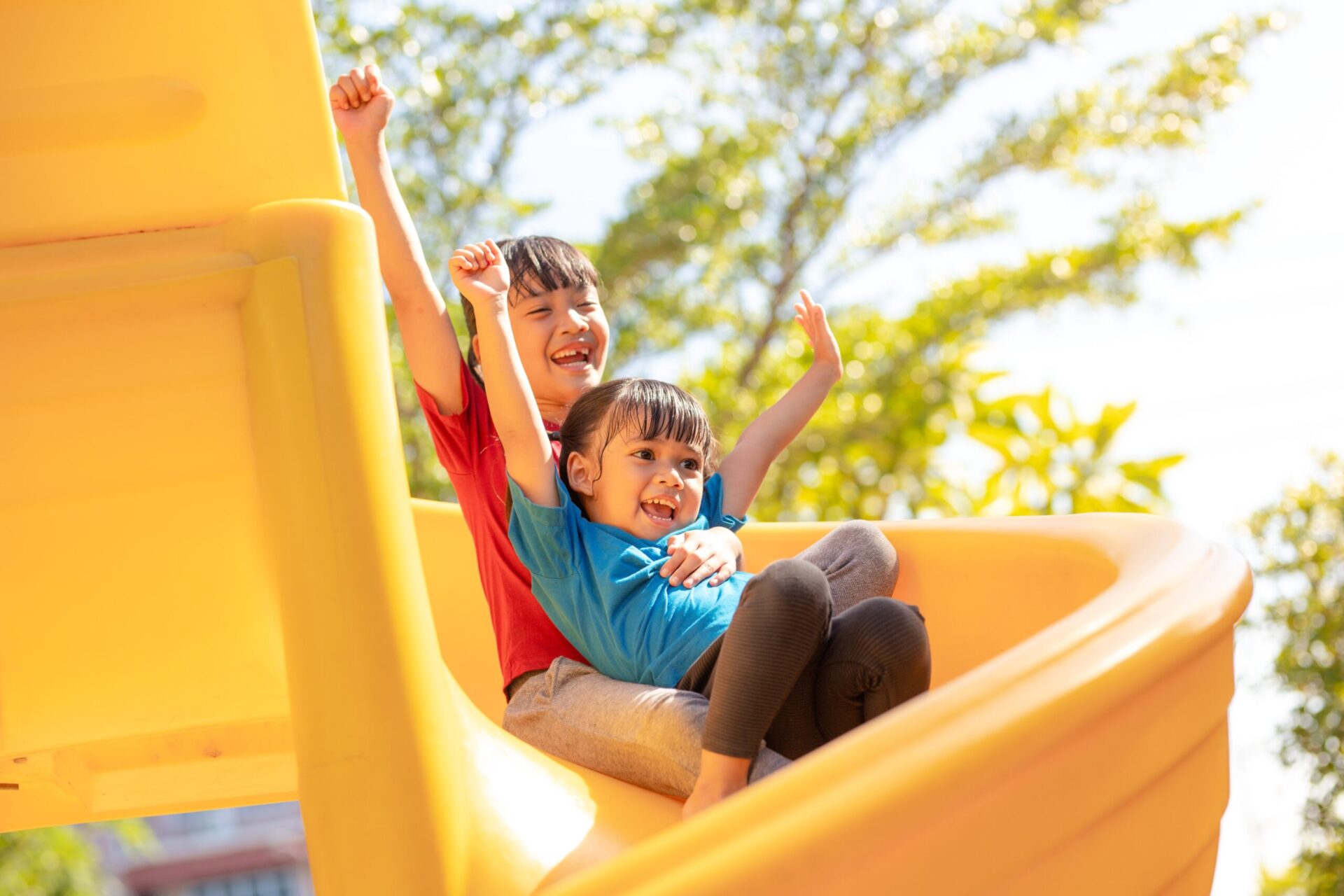two kids sliding down a curly slide together