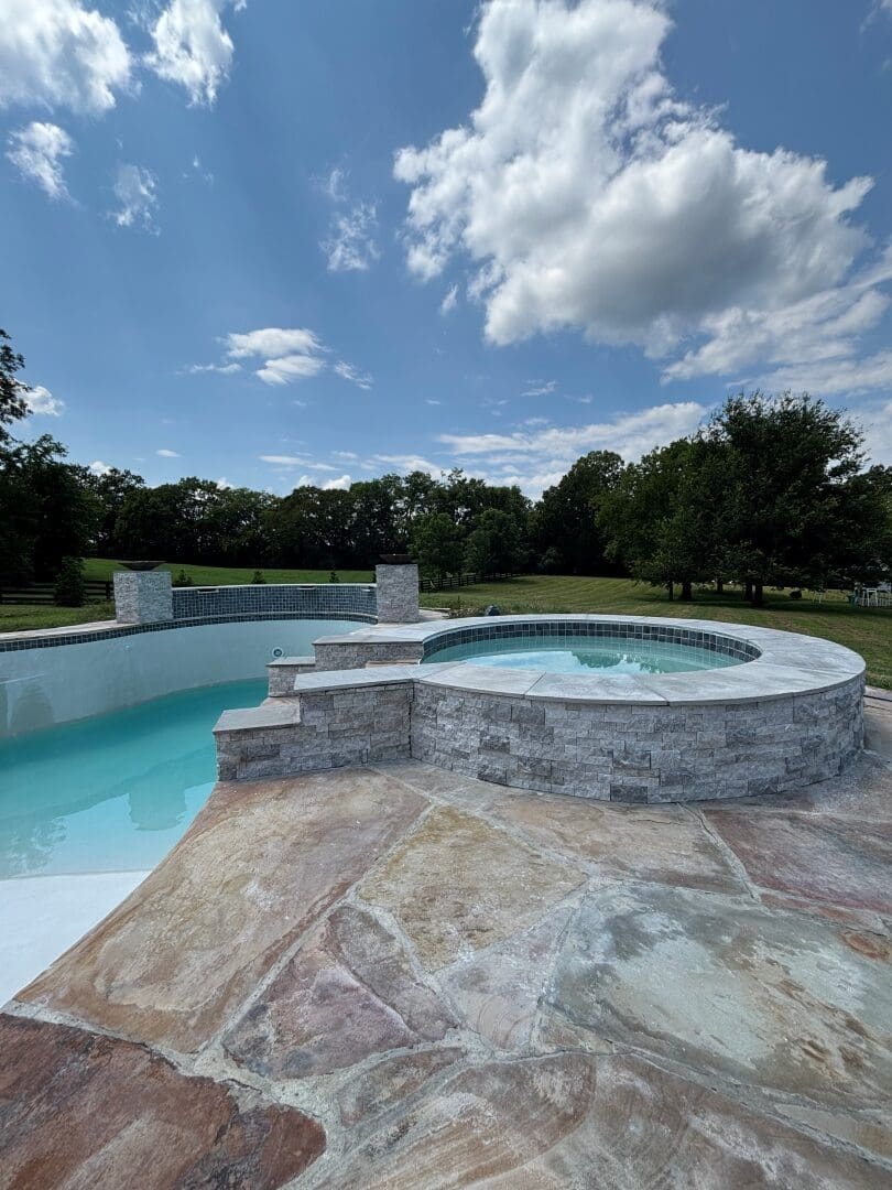 Pool with a raised stacked-stone spa and flagstone deck