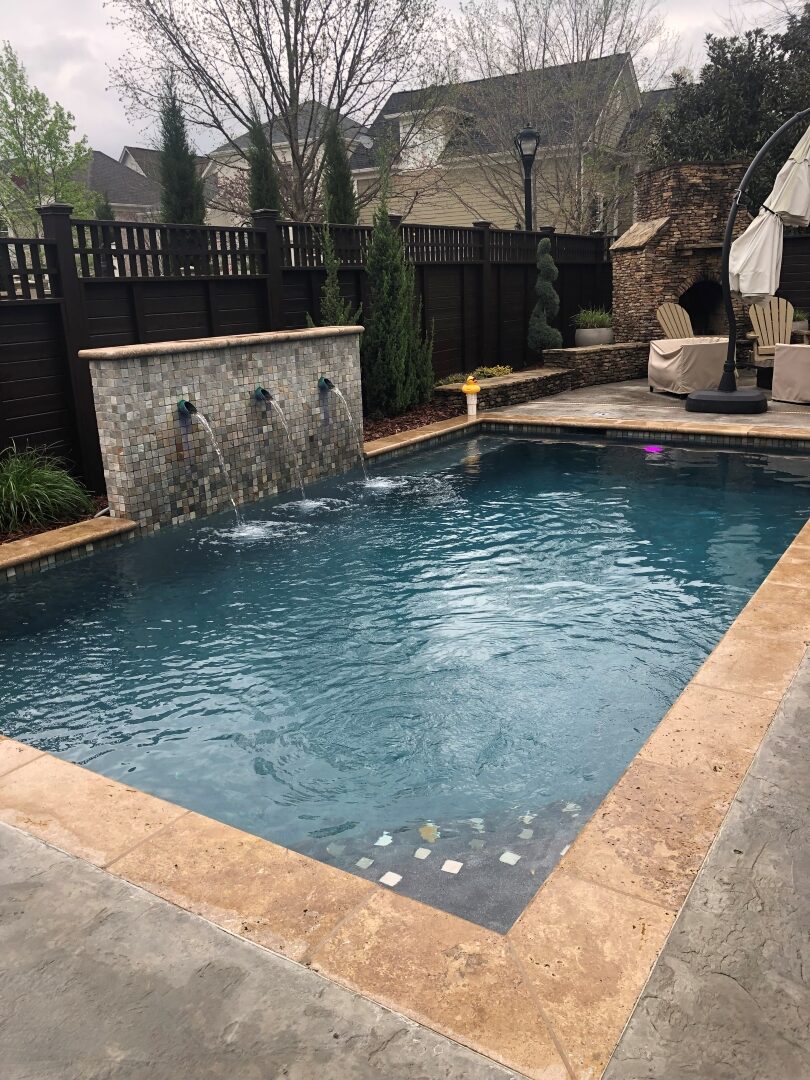 Rectangular pool with a stacked-stone water feature wall and travertine coping