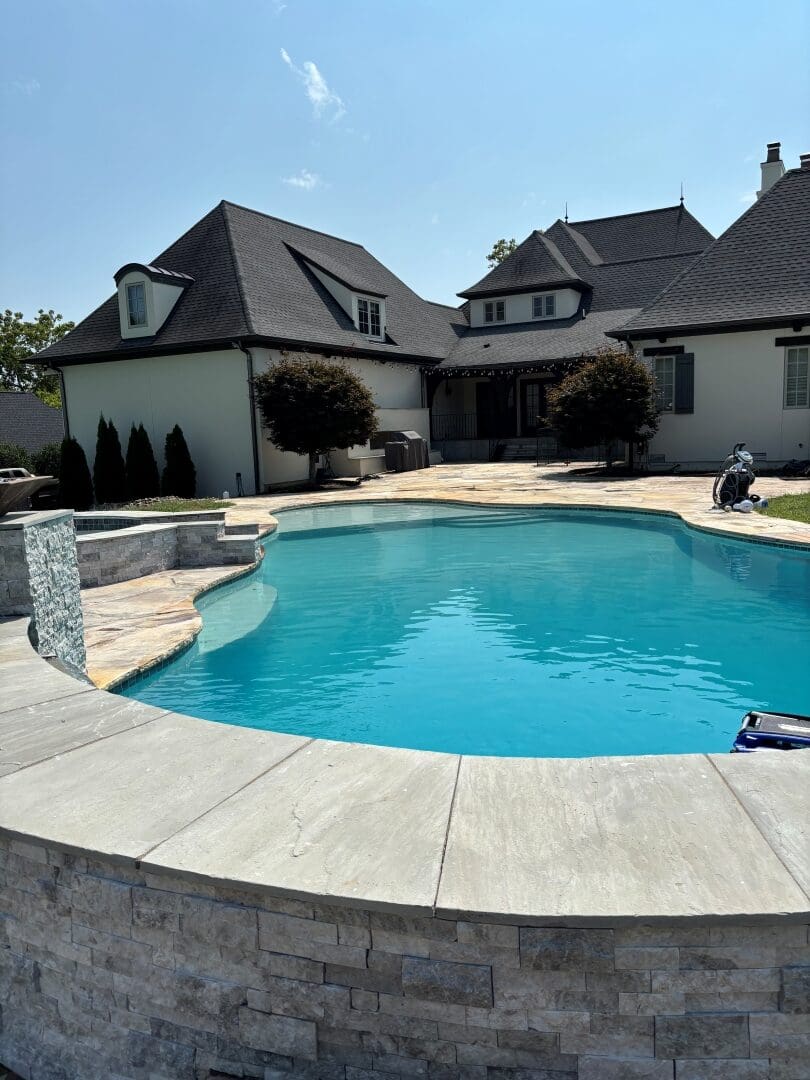 Freeform pool with a stacked-stone raised wall and stone coping