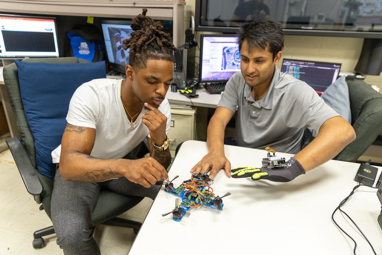 students sitting at a desk working with tools with wires