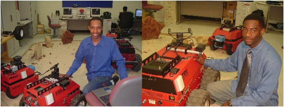 two students sitting on the floor with red robotic machines with next to them