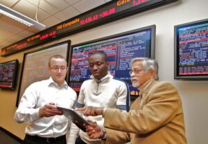 three people standing in a building and looking at a tablet device