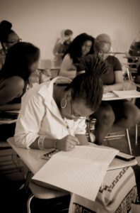 Woman writing poetry in school setting.