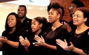 a group of people standing and holding their hands out singing