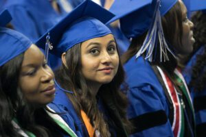 students sitting down wearing caps and gowns 