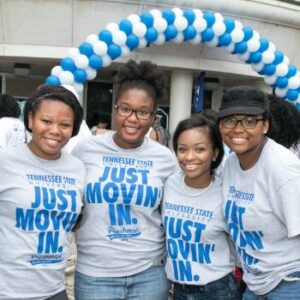 four students standing wearing shirts that say just move it in front of a building
