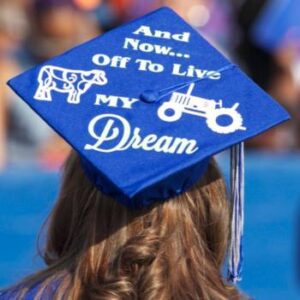 a student sitting down and wearing a graduation cap