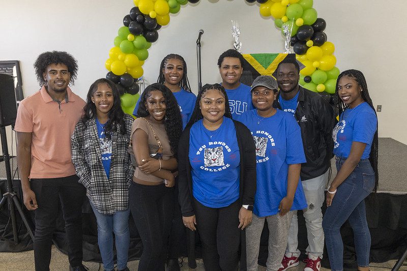 students standing together with ballons and speakers standing behind them