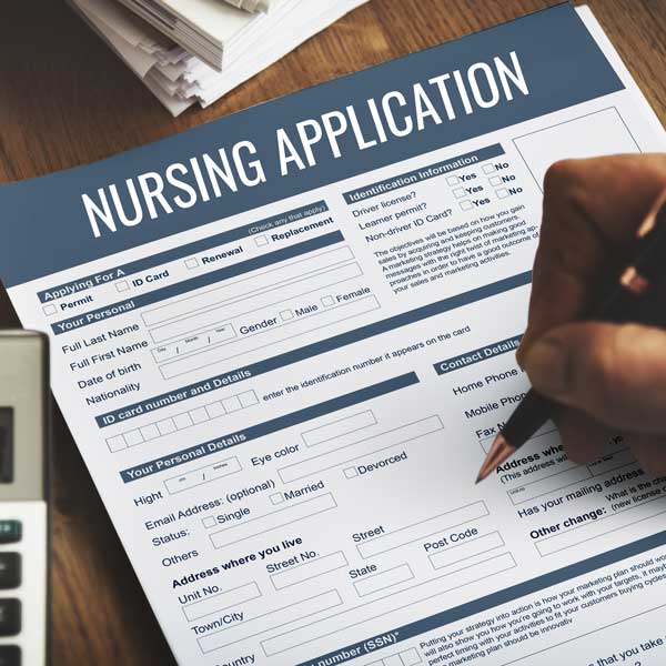 a paper of a nursing application and a person holding a pen