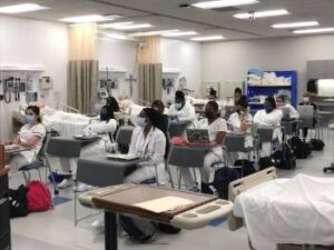 nursing students sitting in a classroom wearing masks and white gowns