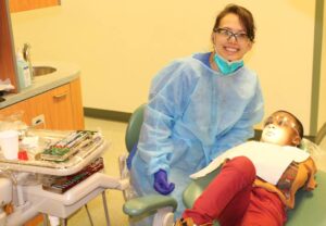 a dentist smiling with a child patient laying on the dental chair