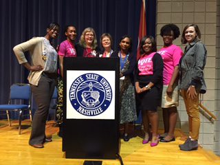 A group of women standing behind a TSU lectern at a seminar.